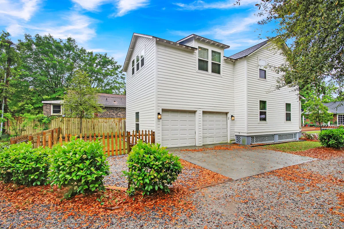 A wide-angle perspective of the exterior, featuring a two-car garage, spacious front porch, and beautifully landscaped yard. The scene showcases ample parking and outdoor gathering space in a friendly, suburban setting.