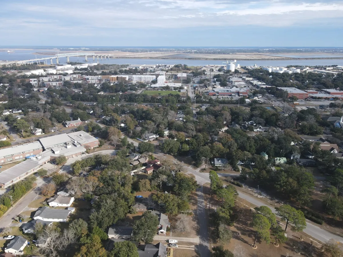 A panoramic view of a scenic bridge over the river, with the downtown Charleston area and residential neighborhoods in the distance, evoking a sense of connection to the city’s history and vibrant community.
