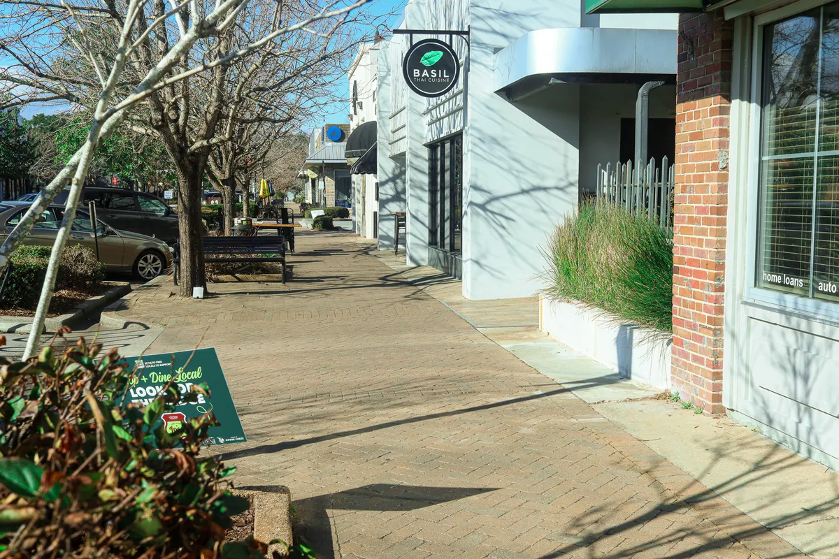 A lively streetscape featuring the Basil restaurant sign, benches along the sidewalk, and a paved walkway, inviting residents to enjoy community amenities and local cuisine.