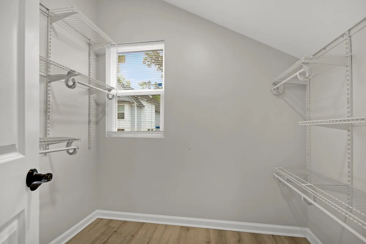 A minimalist interior space with a window and built-in shelves, ideal for storing seasonal items and organizing belongings. The shelves hold baskets and personal items, illustrating purposeful storage solutions integrated into the home.